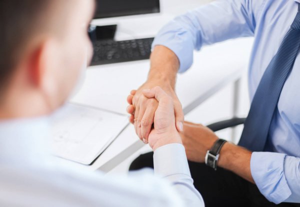 businesss and office concept - two businessmen shaking hands in office